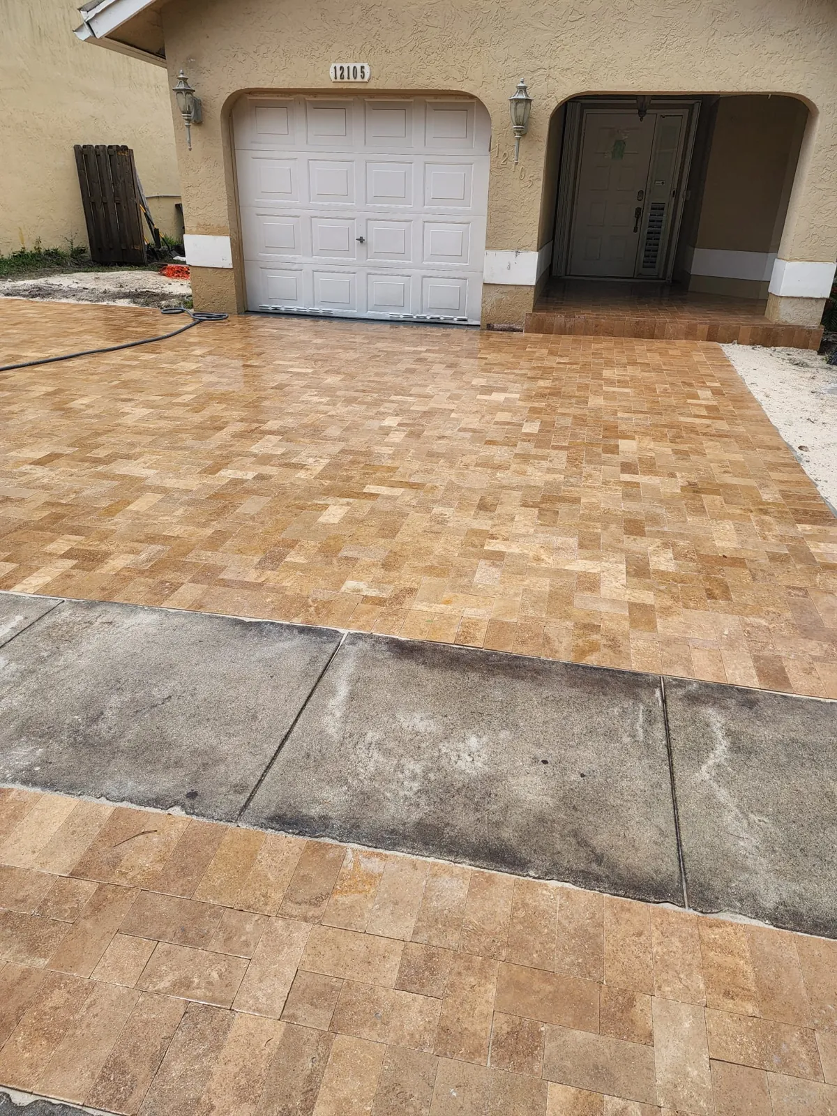 Warm paver apron at a garage entry beside a concrete strip