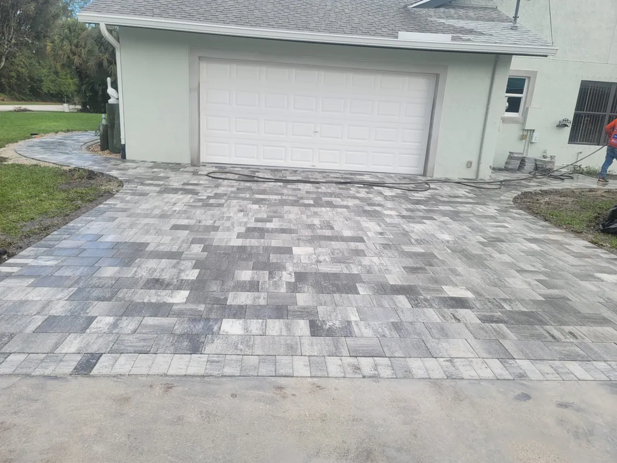 Multi-tone gray pavers laid in front of a white garage door