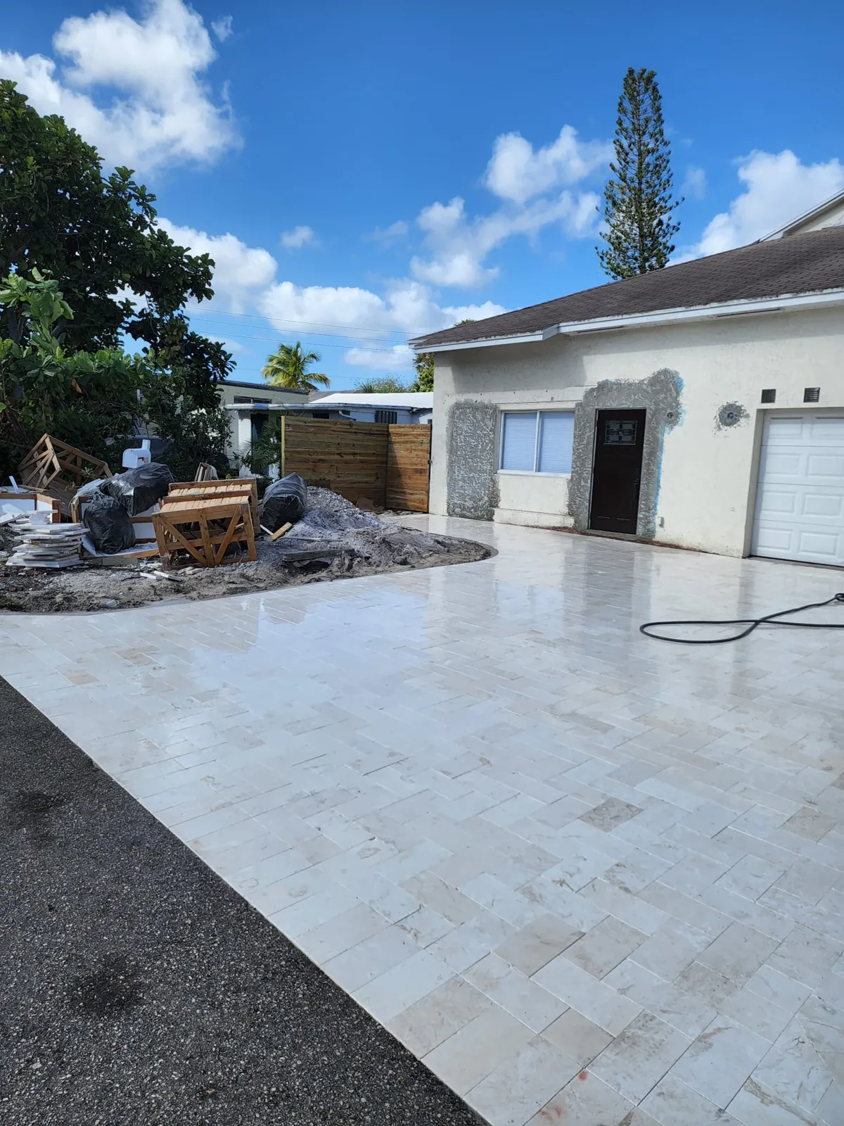 Pale tile driveway surface being installed beside a garage
