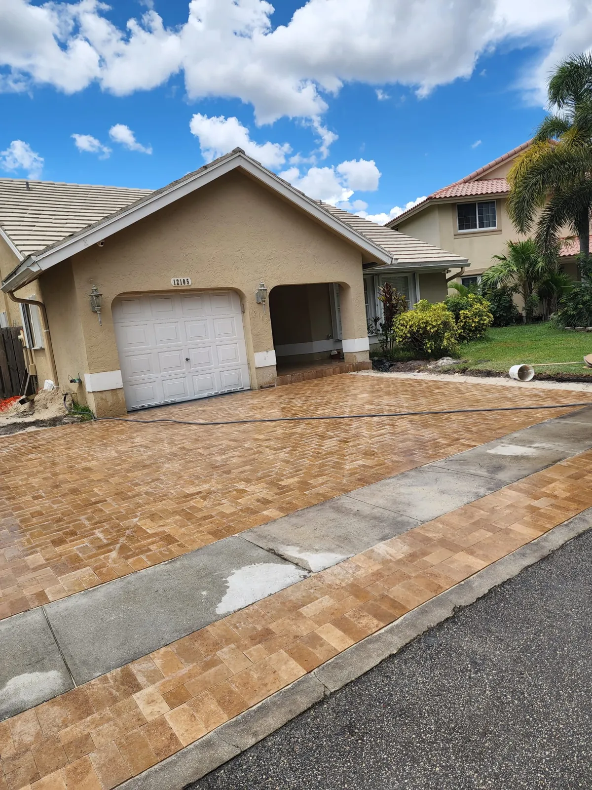 Warm-toned stone paver driveway with a banded border beside the street