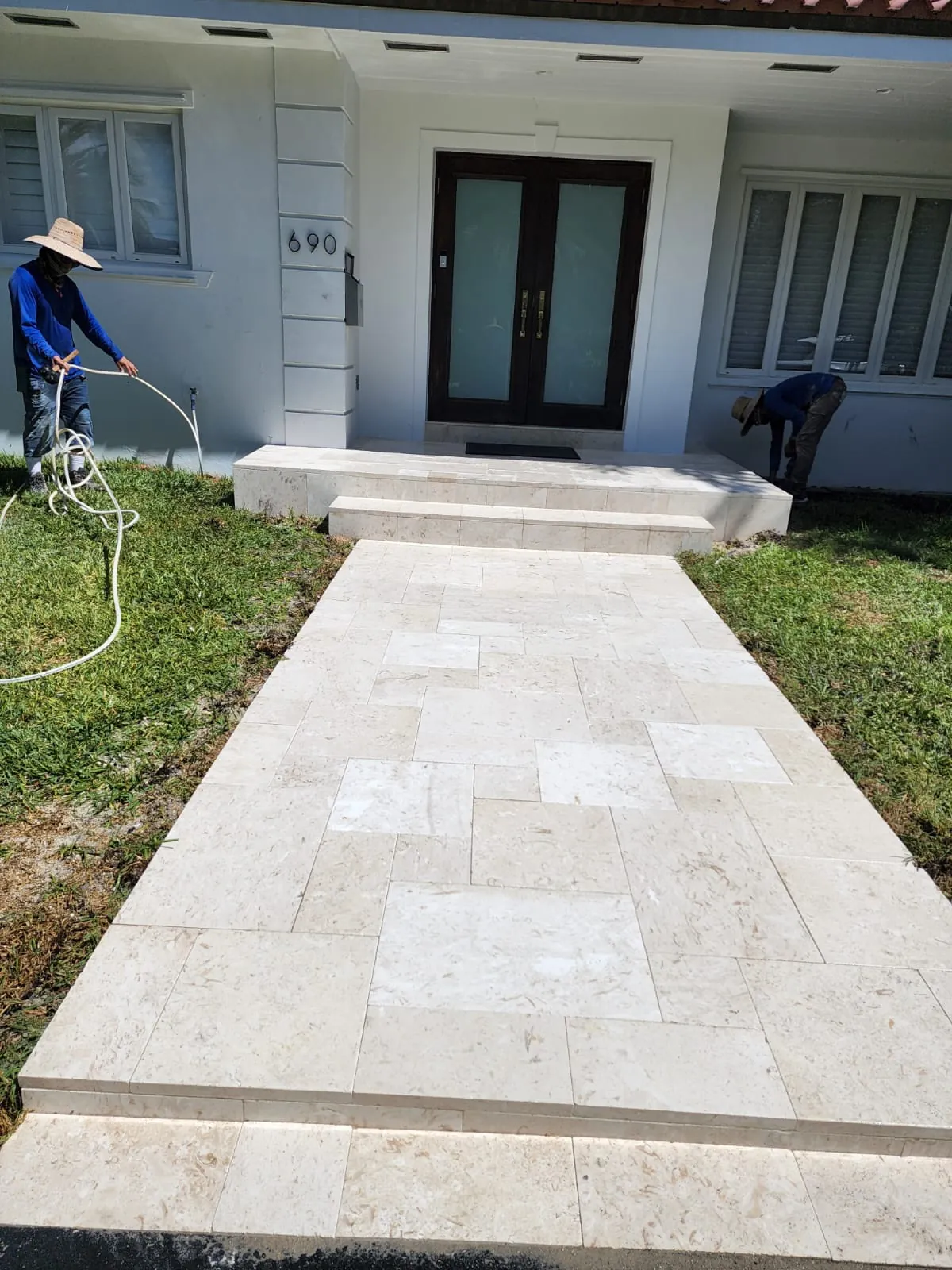 Pale stone walkway and steps leading to a double front door