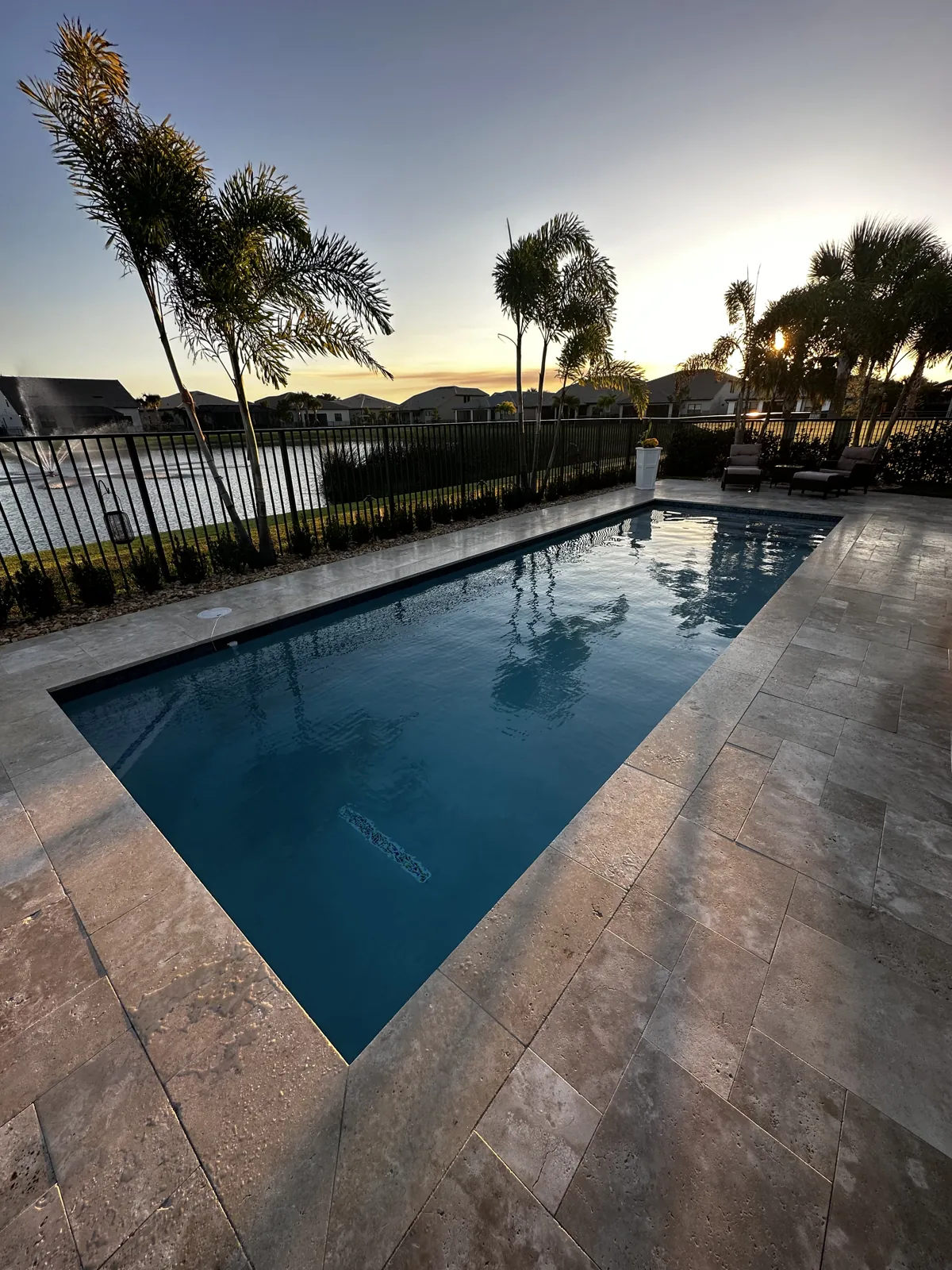 Warm-toned stone pool deck in low evening light with palms behind
