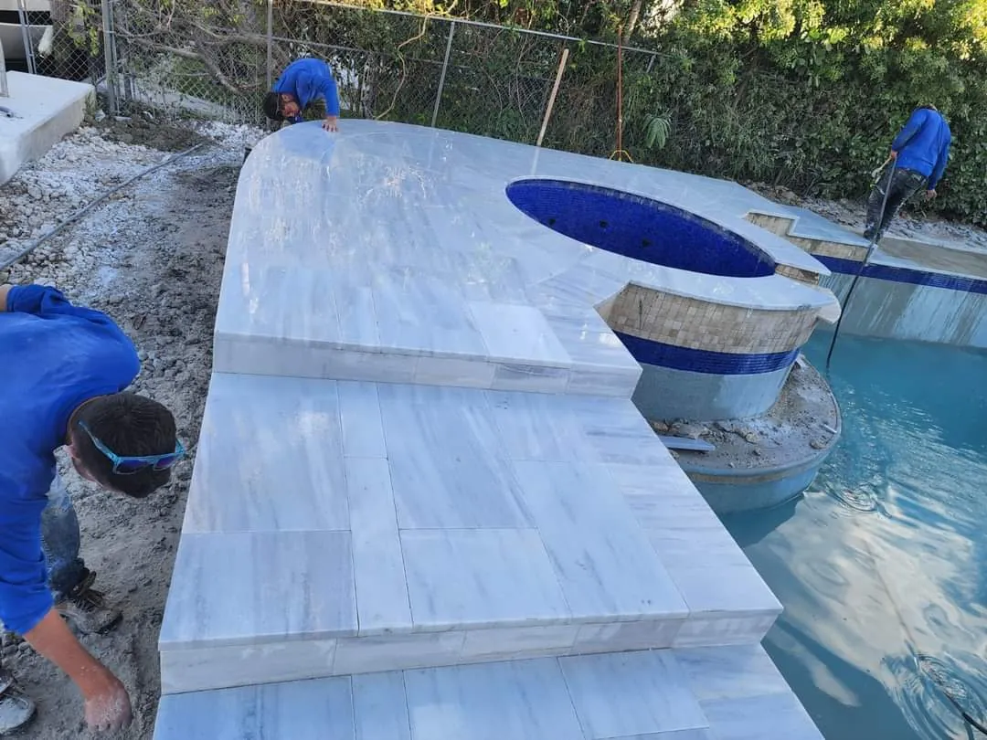 Marble coping slabs being set beside a spa while the crew works
